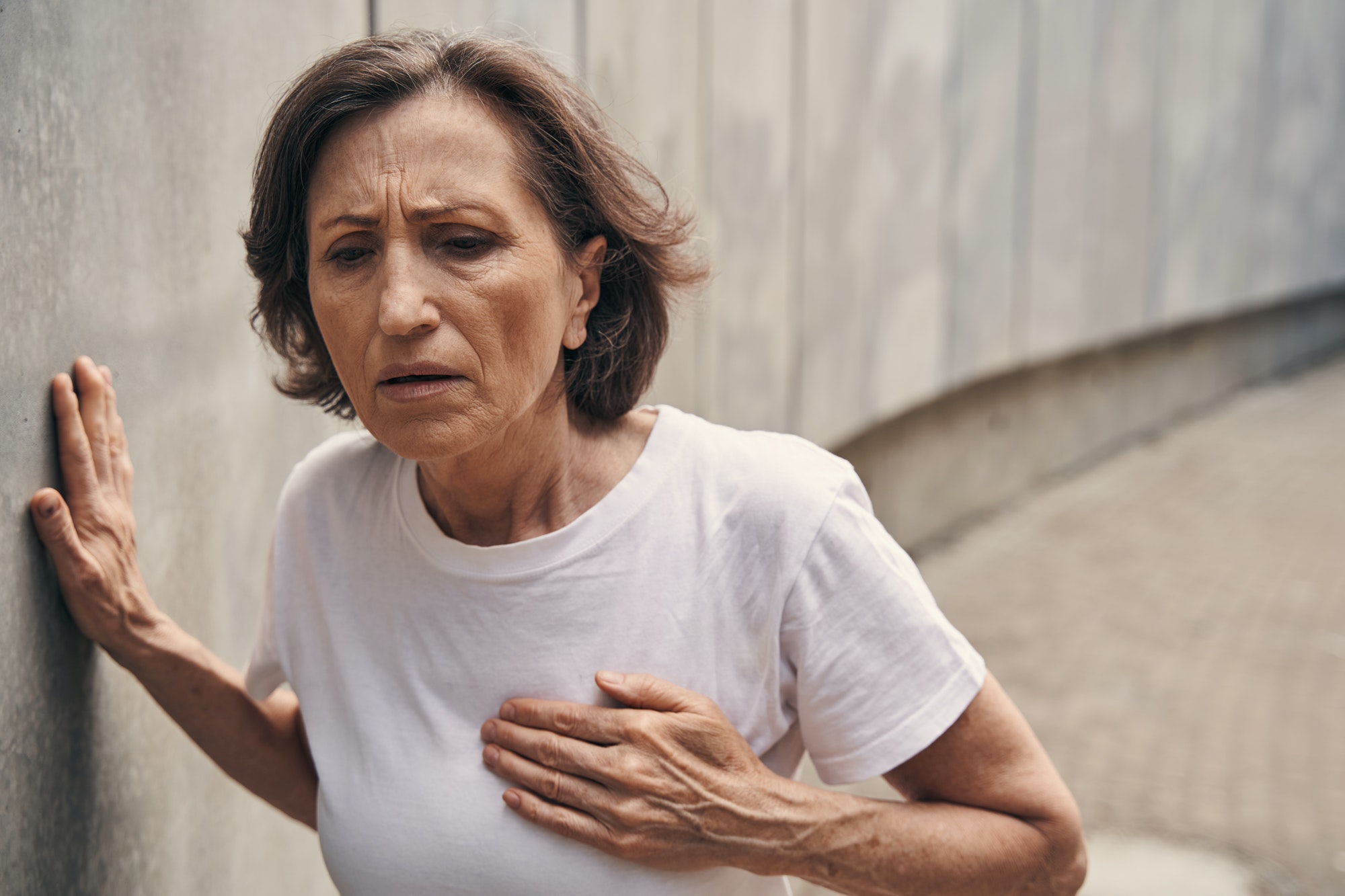 Aged sportswoman feeling pain in chest outdoors